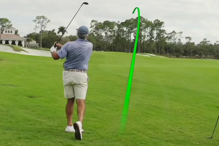 Man using the AnyLie, hitting a flush approach shot, with a baby draw, onto the green.